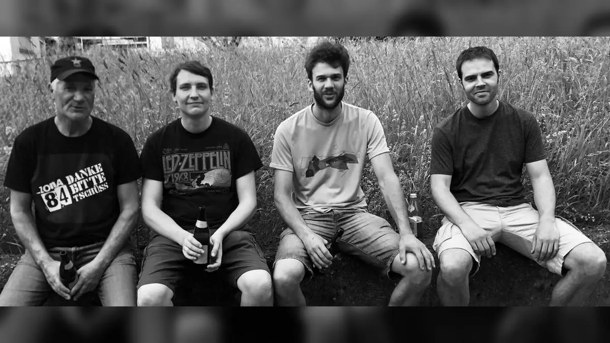 Schwarz-weiß Foto der Band Die Tankstutzen, vier Personen sitzen im Freien mit Getränken