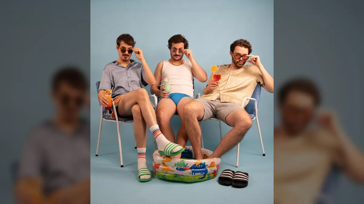 Trio Luigi e Fidelio in sommerlicher Freizeitkleidung mit Sonnenbrillen und bunten Drinks an einem aufblasbaren Pool